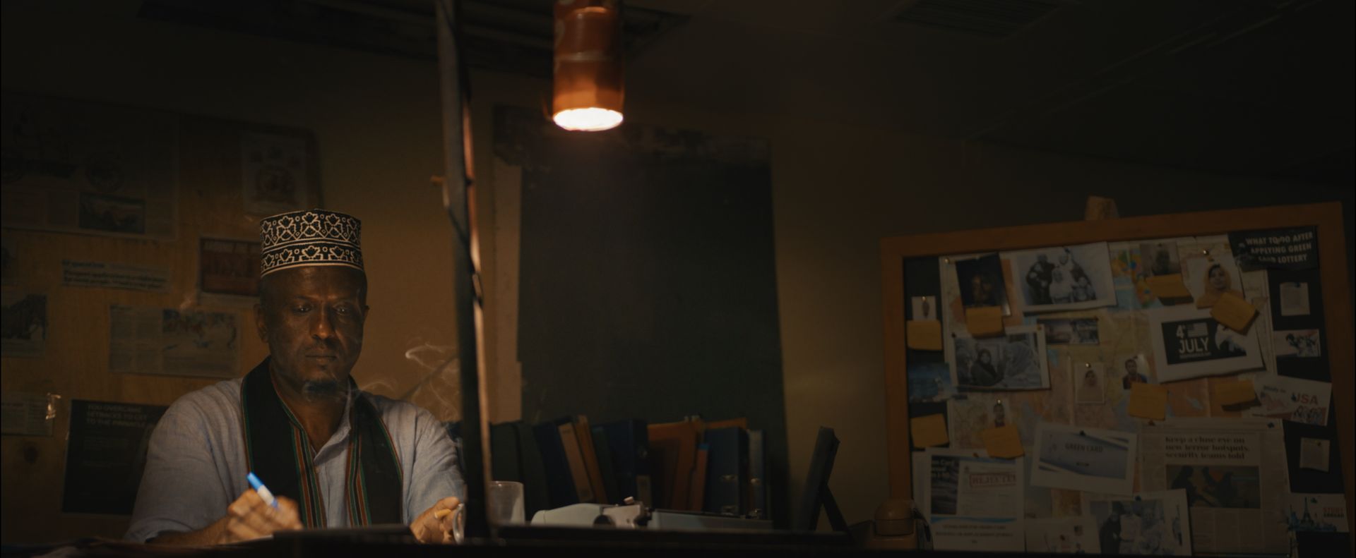 Assad writing at his desk under a lamp, from Bufis – Daydreamers