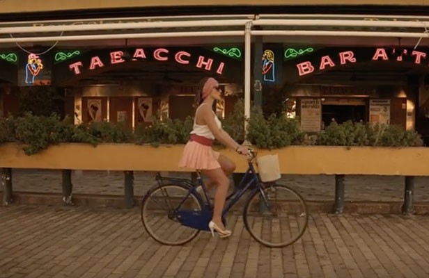 A woman cycles past a neon-lit bar, from Connection House